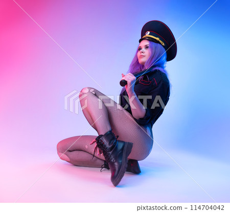 Sexy girl in police military uniform posing in lingerie with a police rubber baton in neon light Sexy girl in police military uniform posing in lingerie with a police rubber baton in neon light 114704042