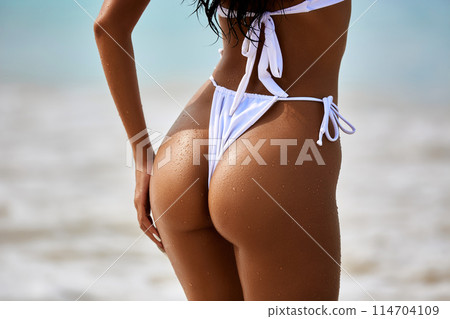 Sexy model's ass in white bikini on the blue water background Sexy model's ass in white bikini on the blue water background 114704109