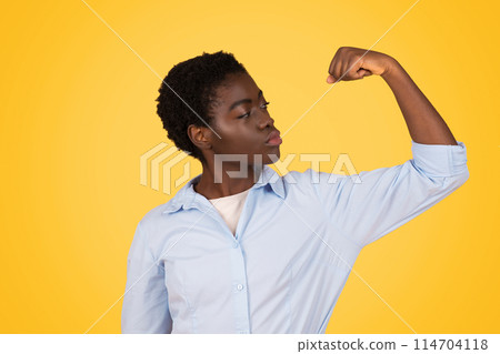 An african american woman showcases her strength and confidence against an isolated yellow background, embodying the empowerment of generation z, or zoomers An african american woman showcases her strength and confidence against an isolated yellow background, embodying the empowerment of generation z, or zoomers 114704118