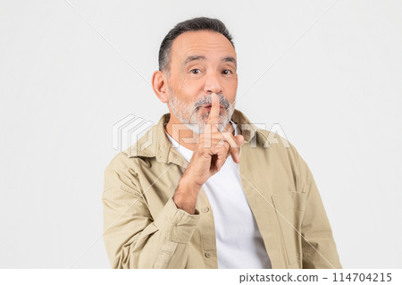 A quiet elderly man with a finger on his lips, isolated on white, encouraging silence, perhaps in a library or during a private moment A quiet elderly man with a finger on his lips, isolated on white, encouraging silence, perhaps in a library or during a private moment 114704215