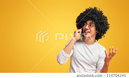 Millennial african guy talking on mobile phone, orange panorama background with free space Millennial african guy talking on mobile phone, orange panorama background with free space 114704245