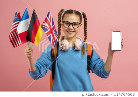 A multilingual or culturally aware teen girl displays a smartphone screen alongside international flags on a pink background 114704508