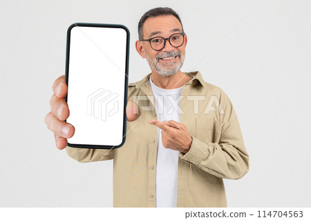 An elderly man confidently shows a blank smartphone screen, pointing to it suggesting importance or new content, isolated on a white background An elderly man confidently shows a blank smartphone screen, pointing to it suggesting importance or new content, isolated on a white background 114704563