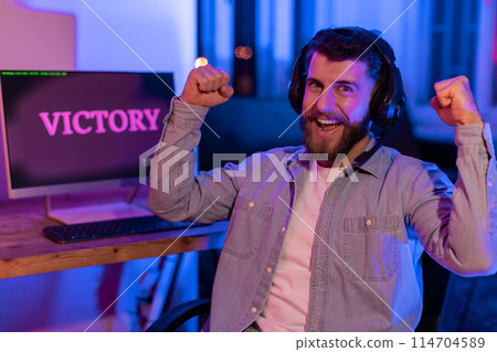 The focus is on a millennial gamer's energetic celebration, highlighting the intense joy and addictive nature of gaming at home 114704589