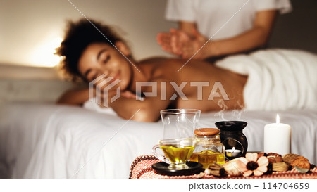 Aroma spa. Woman enjoying massage in luxury spa with candles on foreground 114704659