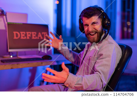 The millennial gamer's frustration is evident as he faces defeat, depicting the emotional rollercoaster of gaming addiction at home The millennial gamer's frustration is evident as he faces defeat, depicting the emotional rollercoaster of gaming addiction at home 114704706