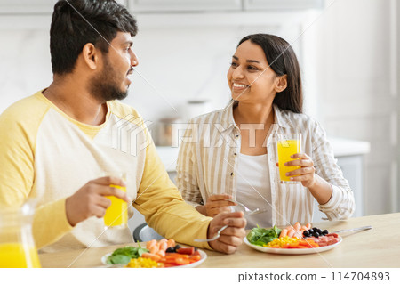 An Indian millennial couple shares a pleasant moment over a healthy meal in a modern kitchen, embodying love and cultural traditions 114704893