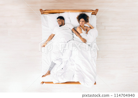 Uncomfortable dream. Upset black woman suffering from her sprawled man in bed, top view with empty space 114704940