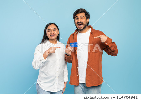 A smiling Indian couple holding and pointing to a credit card, suggesting shopping or financial control 114704941