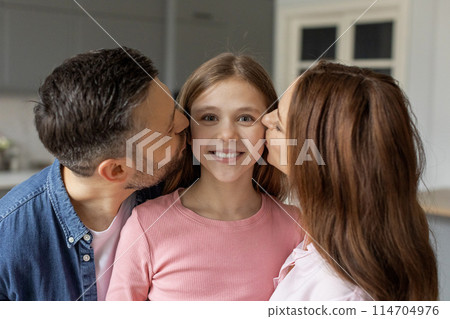 A European family expressing love and affection with parents giving kisses to their smiling daughter at home A European family expressing love and affection with parents giving kisses to their smiling daughter at home 114704976
