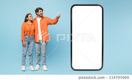 Blank smartphone screen with Indian couple in the background excitedly pointing to the side, ideal for ads 114705069