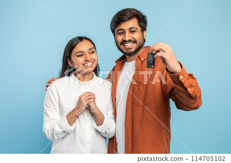 Content Indian couple showing off a car key, implying a new vehicle purchase or ownership on blue 114705102