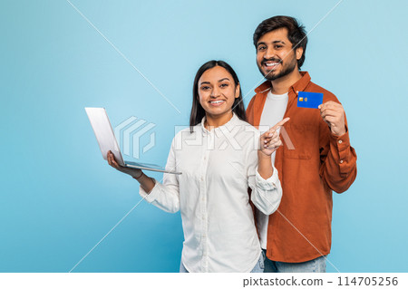 Eastern couple presents a laptop and a credit card, suggesting online shopping or electronic payment 114705256