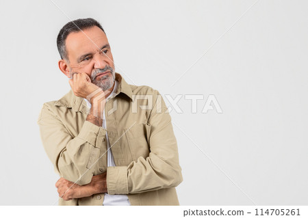 A senior man with a beard appears contemplative, resting his face on his hand against a white background His expression suggests deep thought or concern 114705261