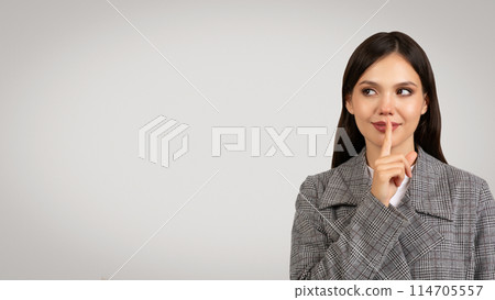 Pensive businesswoman in gray plaid blazer with finger on lips, looking away at free space thoughtfully, suggesting silence or contemplation, on light background Pensive businesswoman in gray plaid blazer with finger on lips, looking away at free space thoughtfully, suggesting silence or contemplation, on light background 114705557