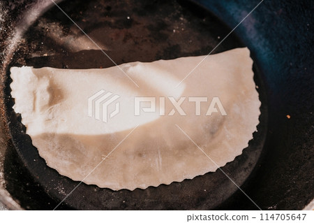 woman's hands making qutab or chebureki with a rolling pin and minced meat onion in dough for culinary concepts related to Azerbaijani, Tatar and Greek cuisine, as well as empanadas in Latin America. woman's hands making qutab or chebureki with a rolling pin and minced meat onion in dough for culinary concepts related to Azerbaijani, Tatar and Greek cuisine, as well as empanadas in Latin America. 114705647