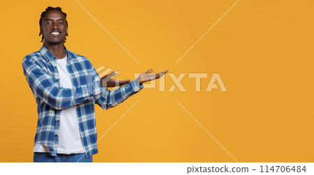 Look There. Happy Young Black Guy Pointing Aside At Copy Space With Two Hands, Cheerful African American Guy Demonstrating Free Place For Advertisement While Standing Isolated On Yellow Background Look There. Happy Young Black Guy Pointing Aside At Copy Space With Two Hands, Cheerful African American Guy Demonstrating Free Place For Advertisement While Standing Isolated On Yellow Background 114706484