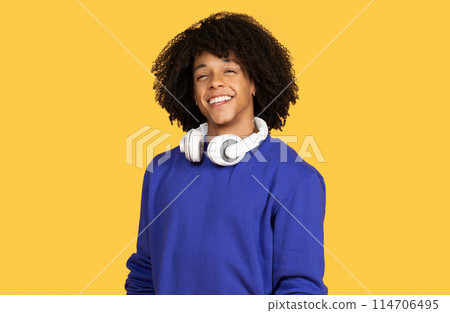 Portrait Of Handsome Young Black Guy With Headphones Around Neck Posing Isolated Over Yellow Background, Happy Cheerful Millennial African American Man Looking And Smiling At Camera, Copy Space 114706495