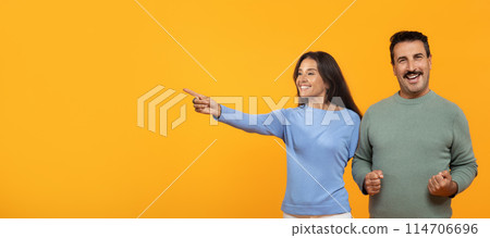 Glad senior caucasian man celebrate success, win, lady point finger at copy space, isolated on orange studio background, panorama. Victory emotions, good news, sale, ad and offer 114706696