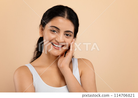 Portrait Of Shy Beautiful Indian Woman Touching Her Smooth Skin And Looking At Camera, Smiling Young Eastern Female With Natural Beauty Standing Isolated Over Beige Studio Background, Copy Space Portrait Of Shy Beautiful Indian Woman Touching Her Smooth Skin And Looking At Camera, Smiling Young Eastern Female With Natural Beauty Standing Isolated Over Beige Studio Background, Copy Space 114706821