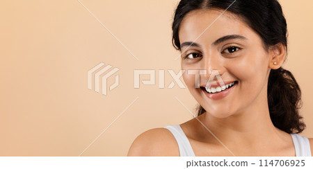 Skincare Concept. Closeup Shot Of Young Indian Woman With Beautiful Smooth Skin, Portrait Of Happy Eastern Female With Nude Makeup Standing Isolated On Beige Studio background, Panorama, Copy Space 114706925
