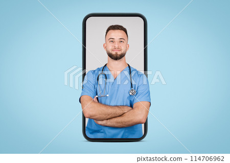 European young male doctor in blue coat, confidently posing with folded arms, displayed on large cellphone screen, set against blue background European young male doctor in blue coat, confidently posing with folded arms, displayed on large cellphone screen, set against blue background 114706962