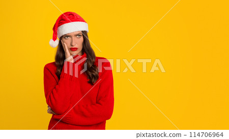 European woman with red Santa hat poses with displeased expression against yellow studio backdrop, embodying expressing disappointment and stress of seasonal holiday shopping. Panorama, empty space European woman with red Santa hat poses with displeased expression against yellow studio backdrop, embodying expressing disappointment and stress of seasonal holiday shopping. Panorama, empty space 114706964
