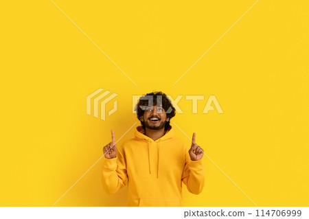Advertisement, offer, deal. Happy handsome curly bearded millennial indian guy wearing casual outfit pointing up at copy space above his head isolated on yellow background Advertisement, offer, deal. Happy handsome curly bearded millennial indian guy wearing casual outfit pointing up at copy space above his head isolated on yellow background 114706999