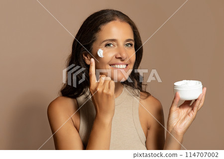 Glad caucasian senior lady show jar of cream, enjoy beauty care, anti-wrinkle treatment with cosmetics and spa procedures at home, isolated on beige studio background. Moisturize, rejuvenation Glad caucasian senior lady show jar of cream, enjoy beauty care, anti-wrinkle treatment with cosmetics and spa procedures at home, isolated on beige studio background. Moisturize, rejuvenation 114707002
