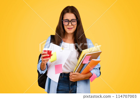 Tired unhappy european teen woman with books, cup of coffee takeaway suffer from fatigue, mistake, cry, isolated on yellow background. Stress, problems at study, overwork Tired unhappy european teen woman with books, cup of coffee takeaway suffer from fatigue, mistake, cry, isolated on yellow background. Stress, problems at study, overwork 114707003