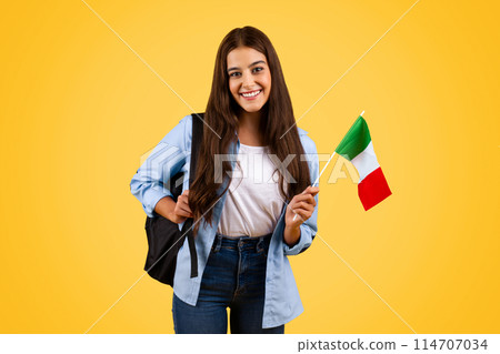 Smiling european teenager student pupil, with Italian flag, enjoy exchange study, courses, isolated on yellow background. Lifestyle, national pride and learning Italian language 114707034