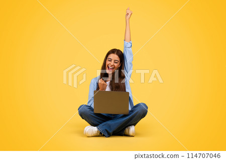Cheerful young european student woman with laptop, rise hand up, isolated on yellow studio background, full length. Success gesture, celebrate win at study, good news reaction Cheerful young european student woman with laptop, rise hand up, isolated on yellow studio background, full length. Success gesture, celebrate win at study, good news reaction 114707046