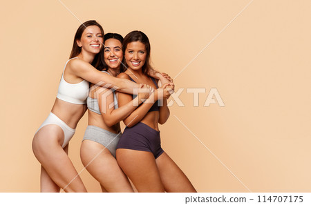 Smiling diverse young women in sports underwear enjoy friendship, diverse beauty, and body positivity, isolate on light background. Unity in diversity, friendship, body care Smiling diverse young women in sports underwear enjoy friendship, diverse beauty, and body positivity, isolate on light background. Unity in diversity, friendship, body care 114707175