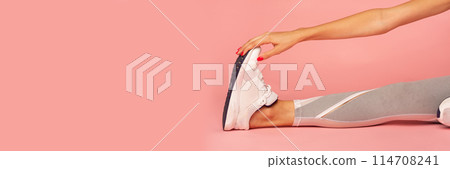 Unrecognizable Lady Stretching Leg Sitting On Floor During Fitness Workout Over Pink Studio Background. Cropped, Panorama With Copy Space 114708241