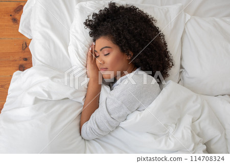 Pretty Hispanic woman is laying down on a bed, her head cradled in her hands. She appears to be deep in thought or contemplation, with a sense of introspection and reflection evident in her posture. Pretty Hispanic woman is laying down on a bed, her head cradled in her hands. She appears to be deep in thought or contemplation, with a sense of introspection and reflection evident in her posture. 114708324