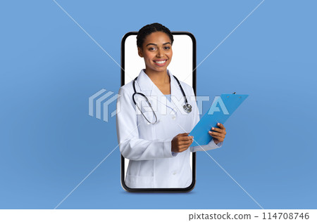 A young black lady doctor stands inside a smartphone screen, engaging in a virtual telemedicine consultation in a bright, modern clinic. 114708746