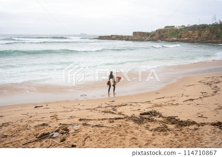Surfer with surfboard gazing sea waves rushing Surfer with surfboard gazing sea waves rushing 114710867