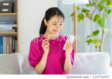 年輕女子在客廳看智慧型手機 114712037