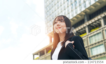 Female business person looking up at the city 114713554