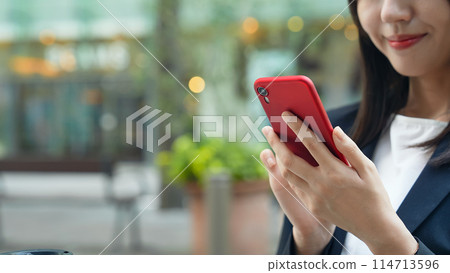Woman looking at a smartphone on a street corner Woman looking at a smartphone on a street corner 114713596