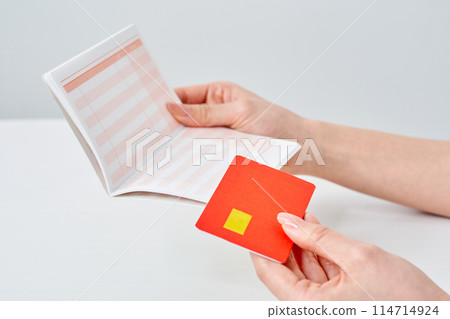 Woman holding bank deposit book and card Woman holding bank deposit book and card 114714924