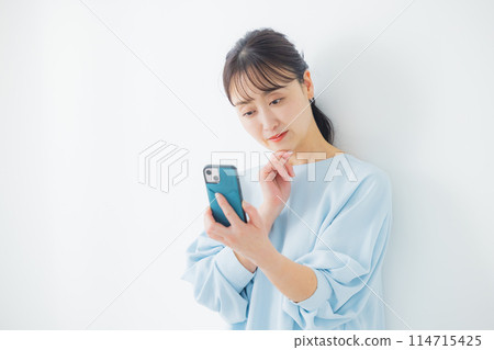 A middle-aged woman operating a smartphone A middle-aged woman operating a smartphone 114715425