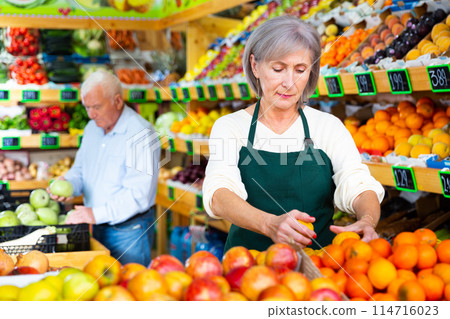 Mature woman supermarket worker and senior man customer in salesroom Mature woman supermarket worker and senior man customer in salesroom 114716023
