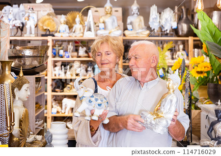 Mature married couple makes choice of buying a indian figurine for country house 114716029