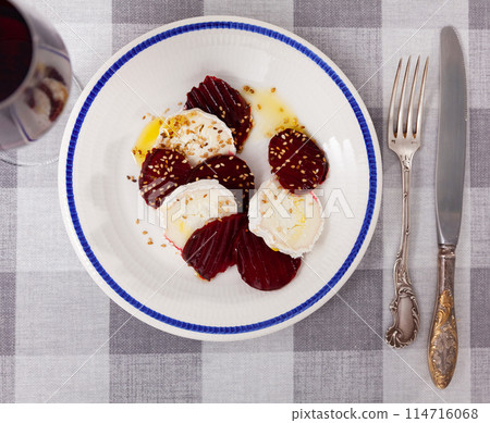 Delicious salad of baked beetroot with creamy goat cheese and decorated sesame seeds serving on plate 114716068