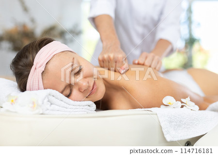 Female masseur works out shoulder and back problem area for female athlete client. Close-up Female masseur works out shoulder and back problem area for female athlete client. Close-up 114716181