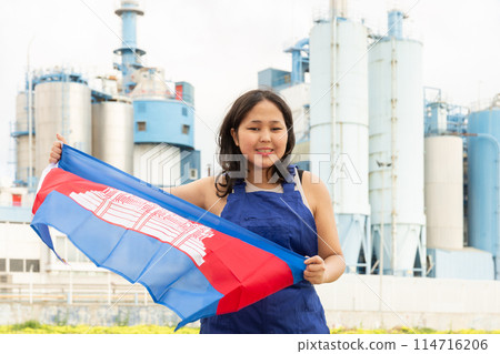 National flag of Cambodia in the hands of girl in overalls against background of modern metallurgical plant National flag of Cambodia in the hands of girl in overalls against background of modern metallurgical plant 114716206