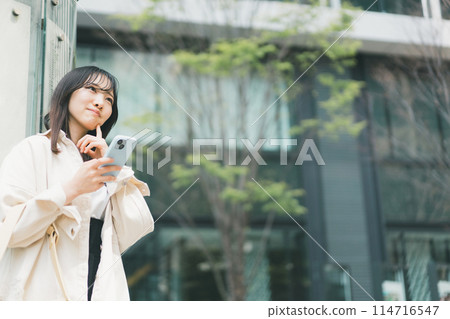 一位拿著智慧型手機的年輕女子對城市中的某些事物感到好奇的場景 114716547