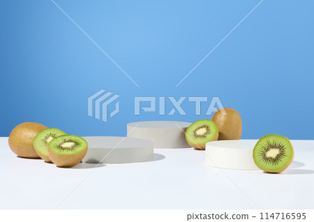Three round podiums in gray and white color featured over blue background with green kiwis. Rich in fiber, kiwi fruit supports digestive regularity 114716595
