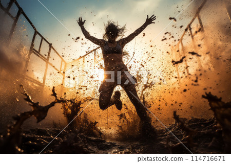 A woman is joyfully leaping in the mud with arms spread wide 114716671